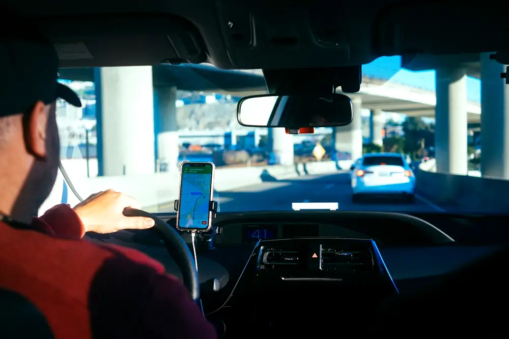 Conductor con la ruta del día en el celular montado en el tablero